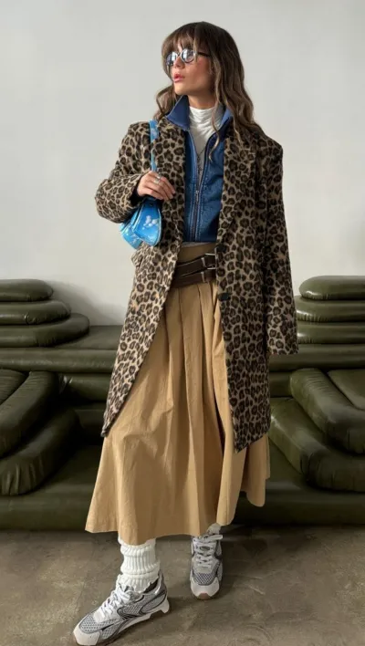 Leopard coat layered over a denim shirt and flowing tan maxi skirt with sneakers