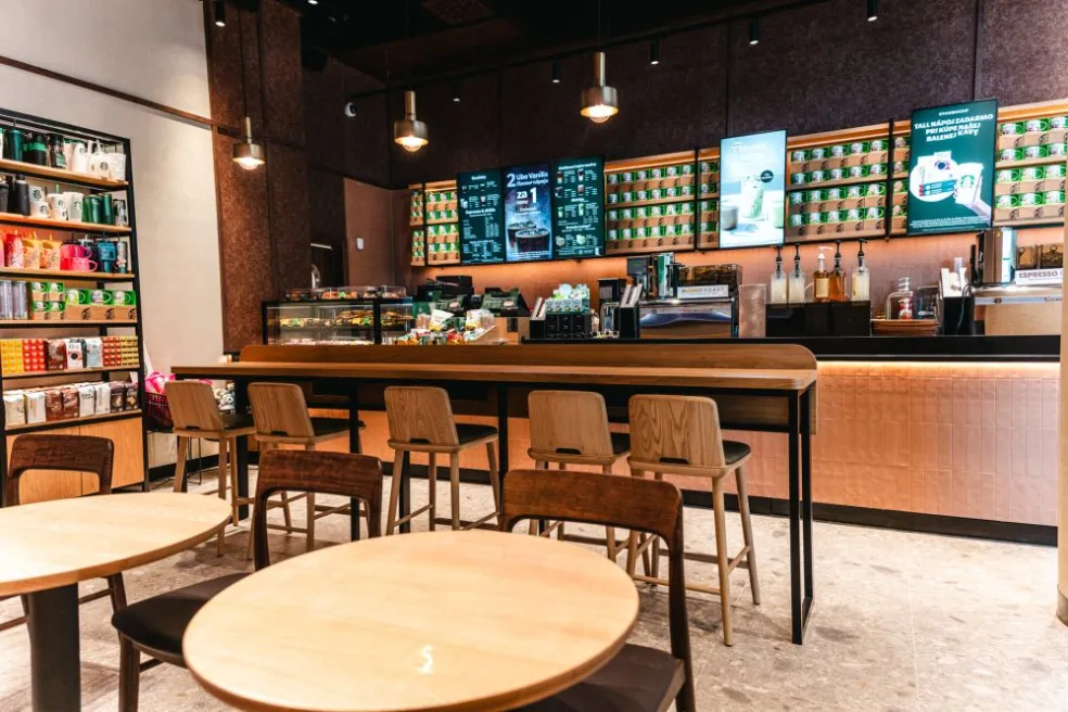 Interiér novej kaviarne Starbucks v Eurovea II s drevenými stoličkami, barovým pultom a ponukou nápojov