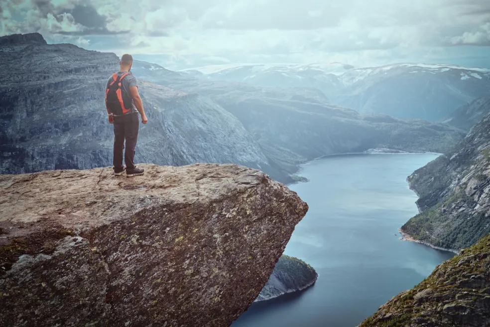 Turista obdivuje nórsky fjord z vyhliadky Trolltunga počas letnej dovolenky