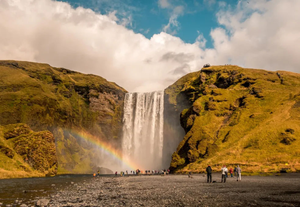 Cestovatelia pri vodopáde Skógafoss na Islande počas slnečného letného dňa