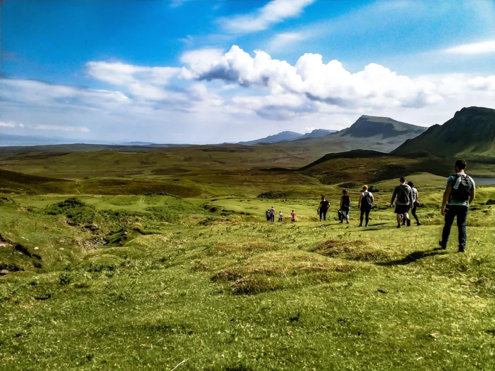 Turisti kráčajú zeleným údolím na ostrove Skye v Škótskej vysočine