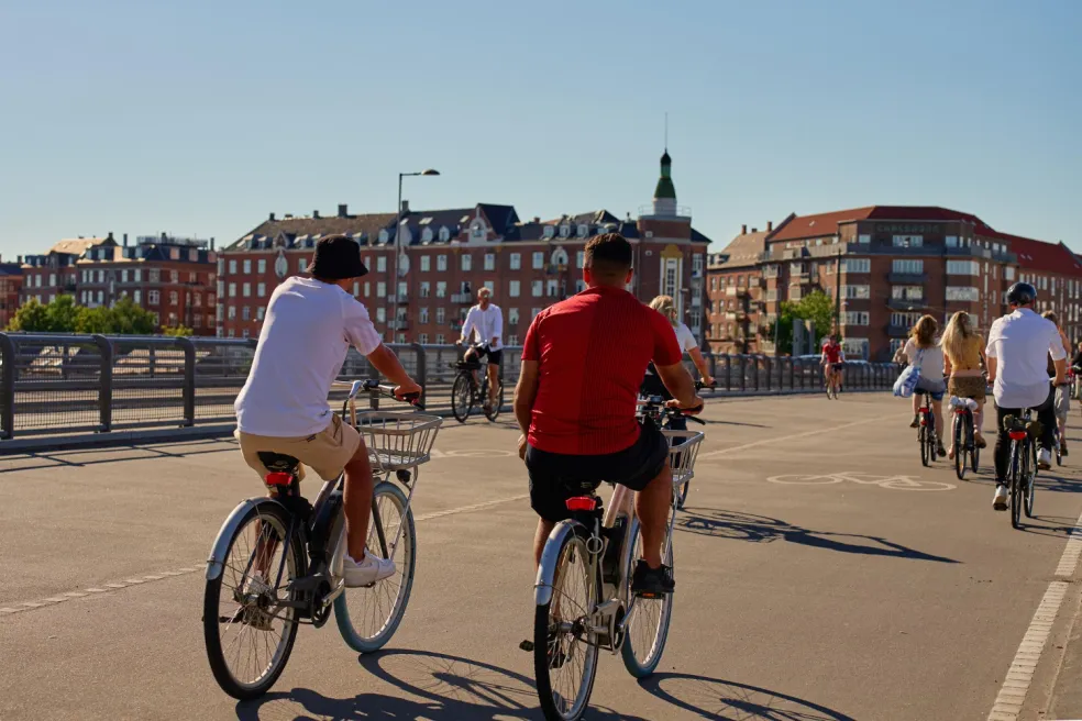 Cyklisti jazdia slnečnými ulicami Kodane počas letnej dovolenky