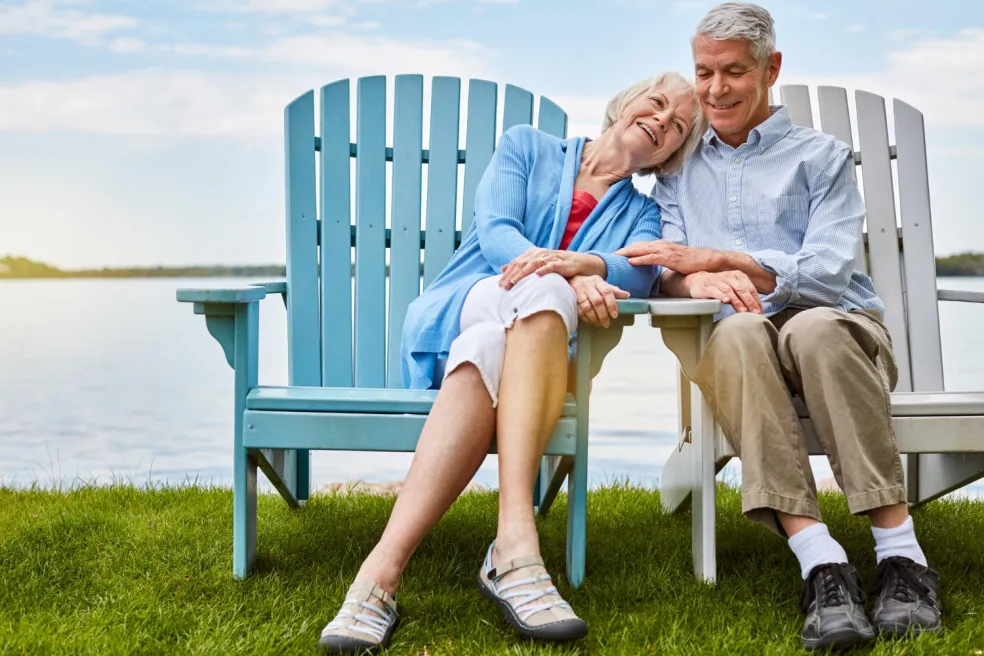 Seniorský pár oddychuje v kreslách pri jazere počas príjemného letného dňa