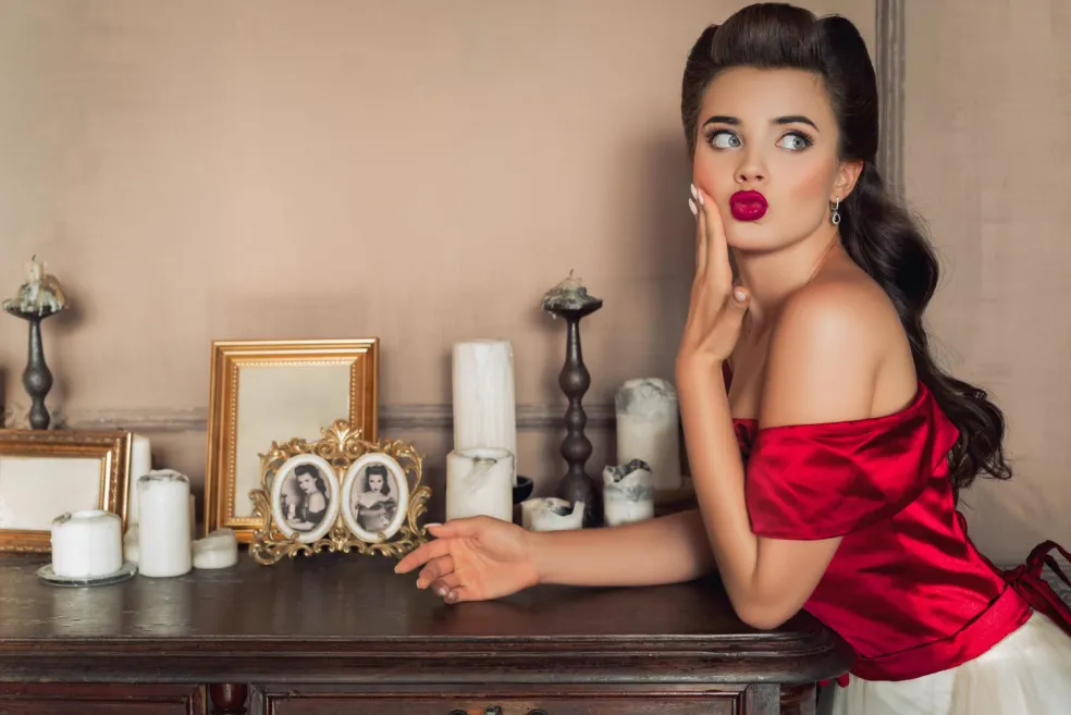 Žena v retro štýle s červenými perami pózuje v interiéri inšpirovanom