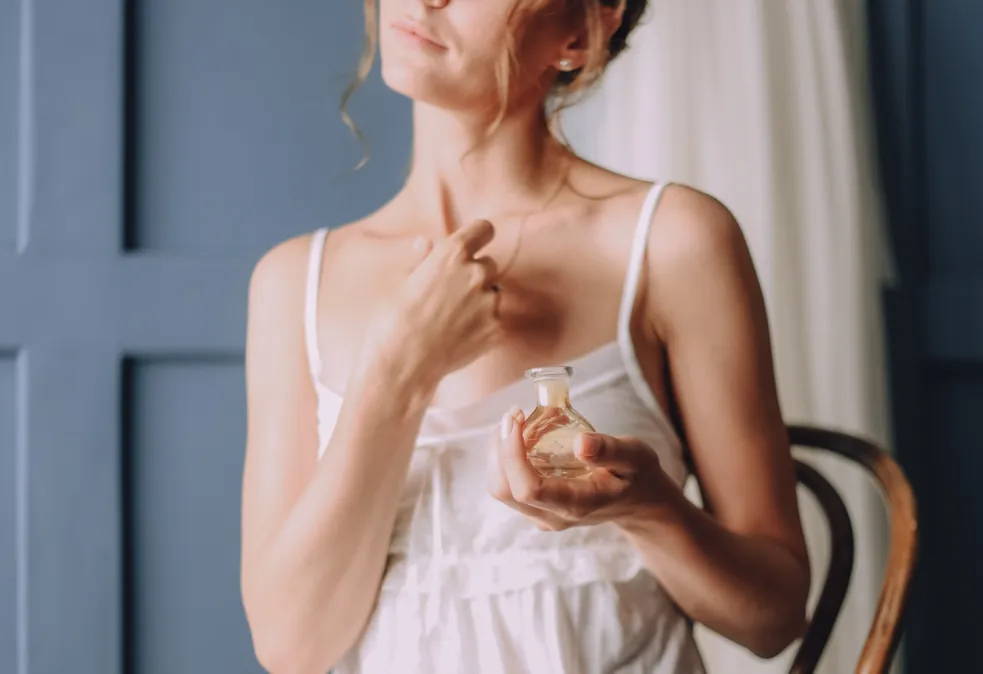 Žena si dáva parfum na pokožku pred opaľovaním – možná fototoxická reakcia na slnko