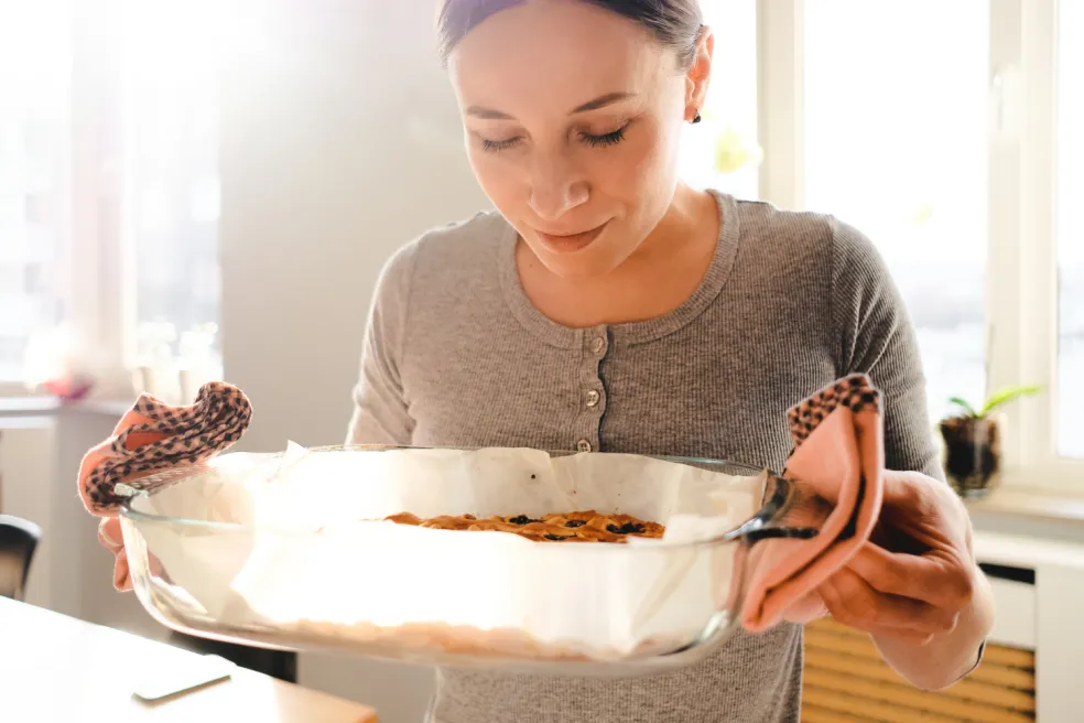 Žena kontroluje čerstvo upečený koláč, či je správne prepečený