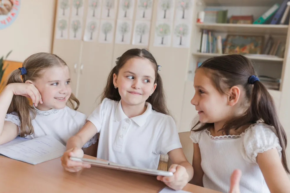 Skupina školákov sedí tesne pri sebe v triede a rozpráva sa, čo zvyšuje riziko prenosu vší medzi deťmi