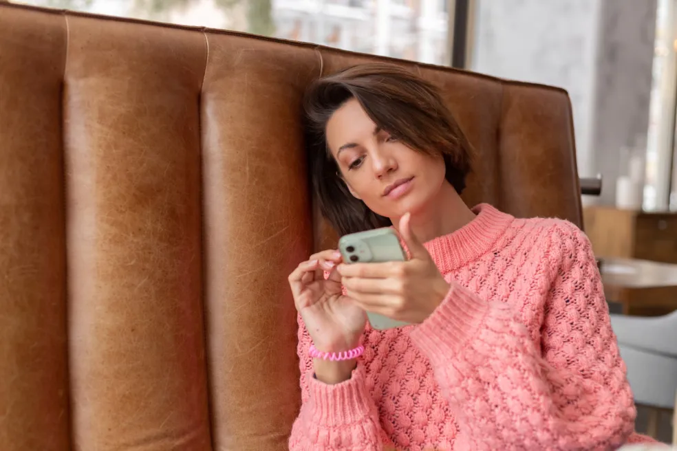 Žena po hádke s partnerom premýšľa nad správou v mobile