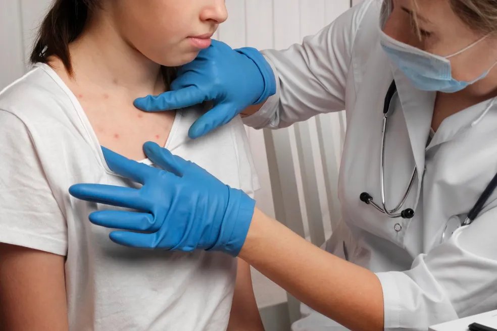 Dermatológ vyšetruje kožnú vyrážku na hrudníku u pacientky