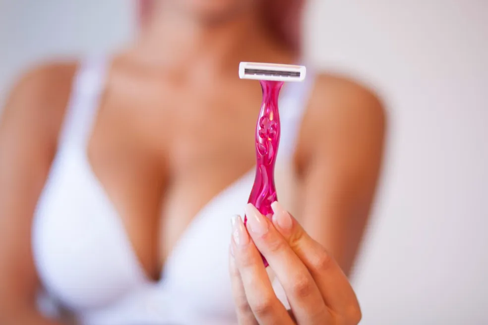 Žena drží holiaci strojček v kúpeľni pred návštevou gynekológa