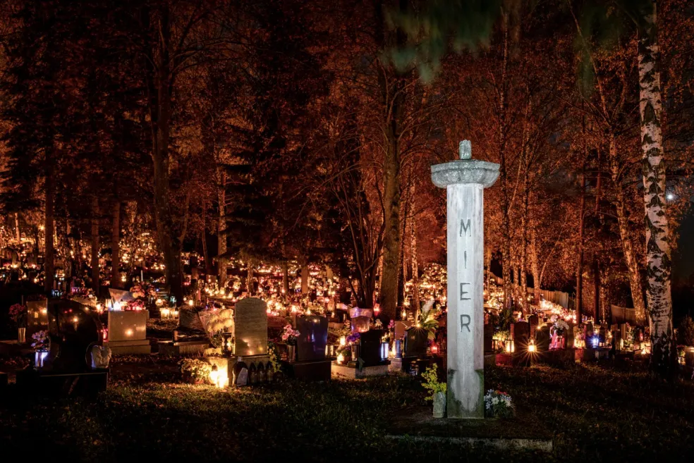 Nočný cintorín osvetlený množstvom sviečok a kahancov medzi hrobmi