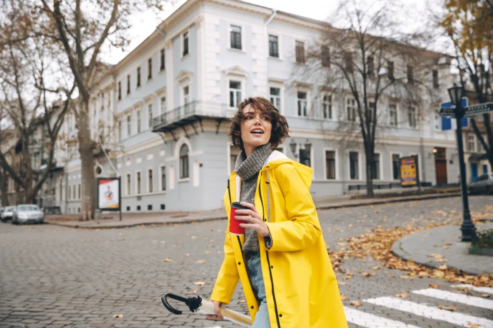 Žena kráča jesenným mestom so šálkou kávy – horoskop pre Leva na október 2026