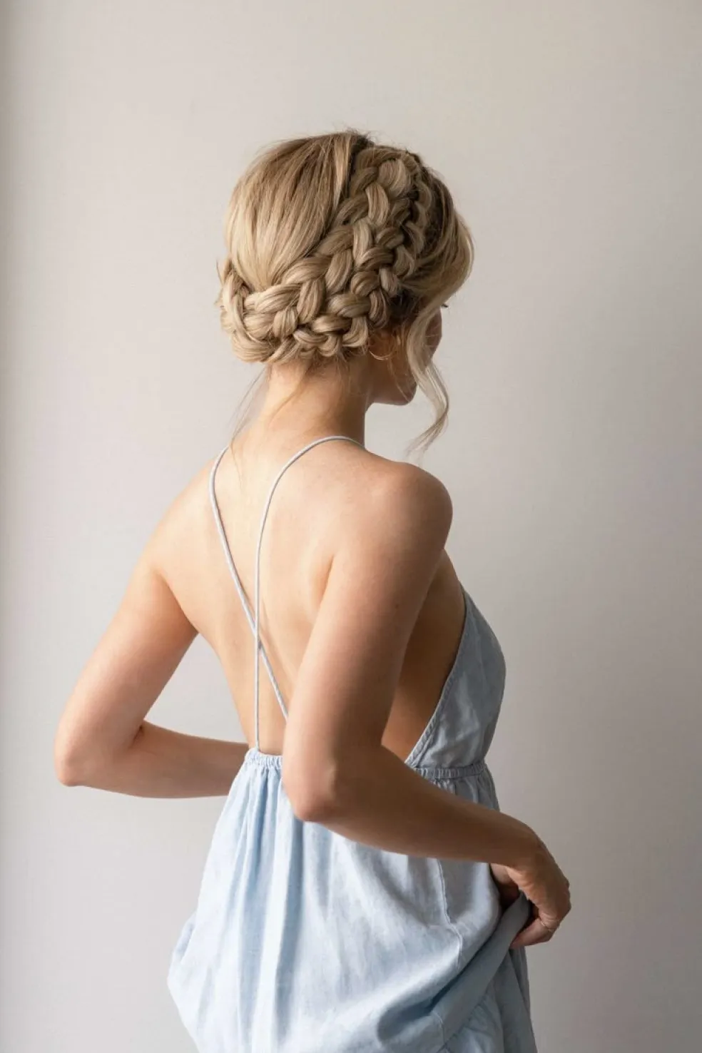 Žena s blond vlasmi upravenými do elegantnej zapletene​j koruny okolo hlavy