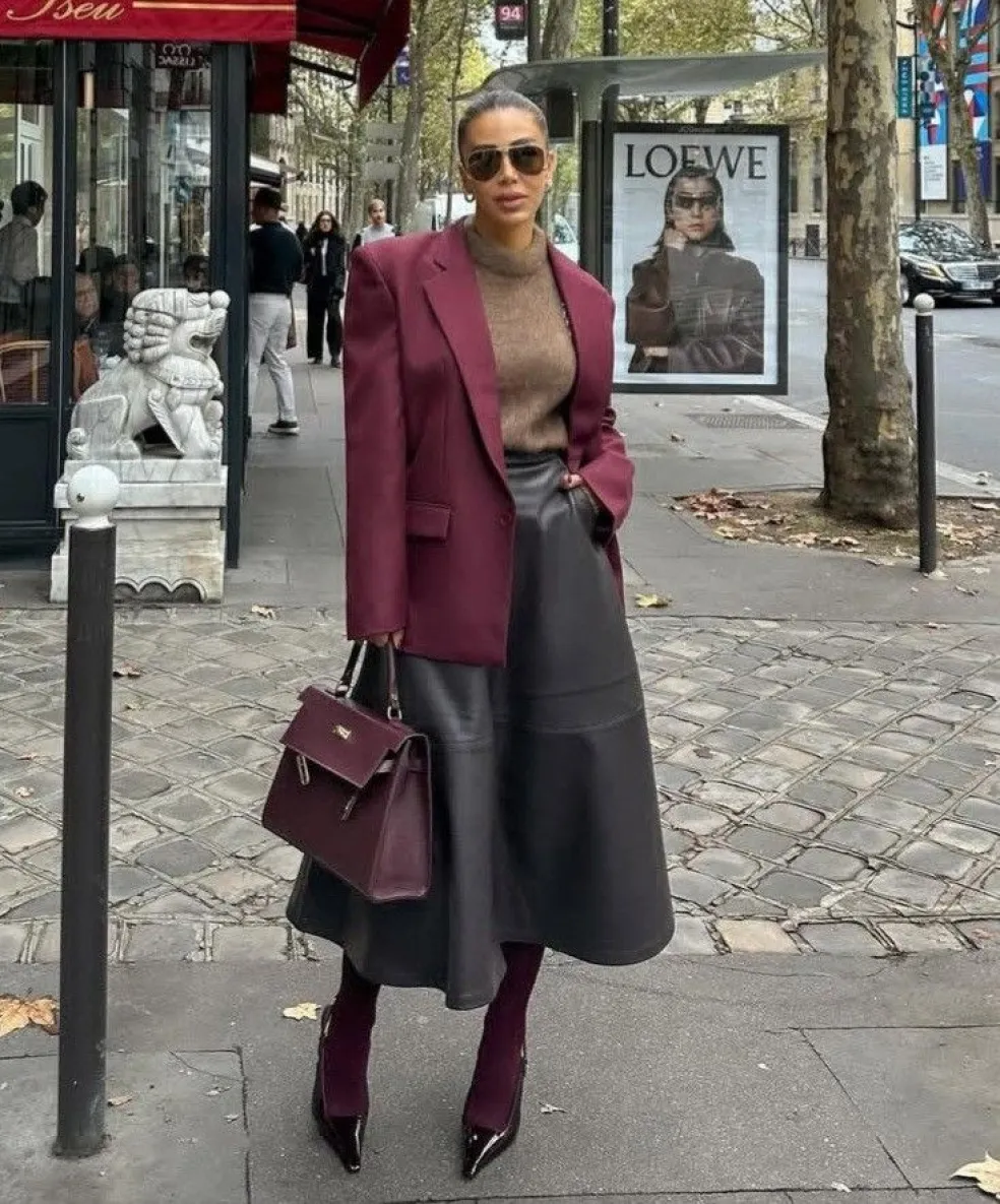 Čierna kožená midi sukňa s bordovým sakom, hnedým rolákom, bordovou kabelkou a čižmami v elegantnom jesennom mestskom outfite