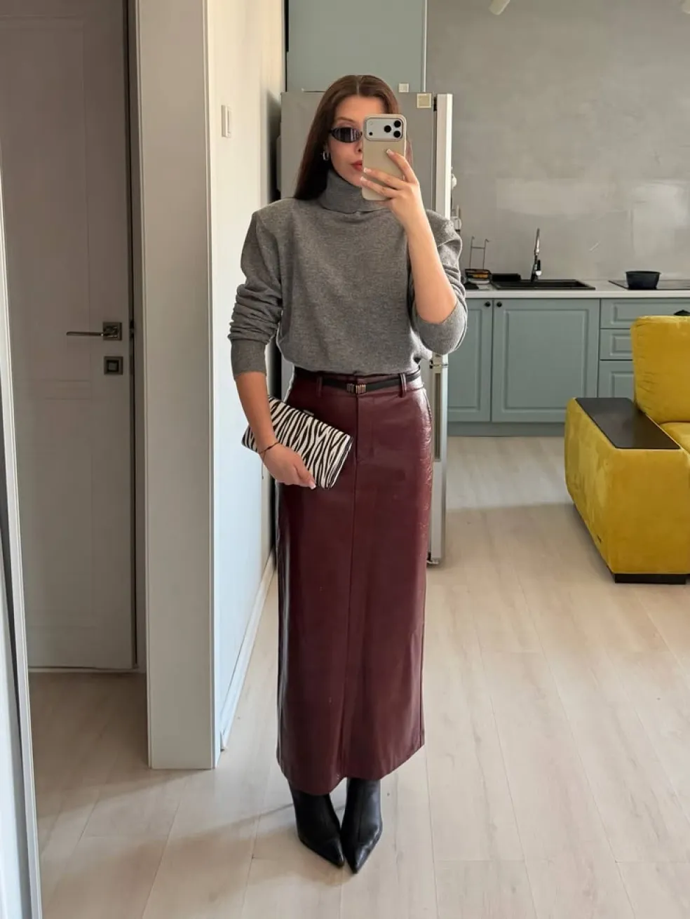 Bordová kožená midi sukňa so sivým rolákom, čiernymi členkovými čižmami a zebra kabelkou v elegantnom jesennom outfite