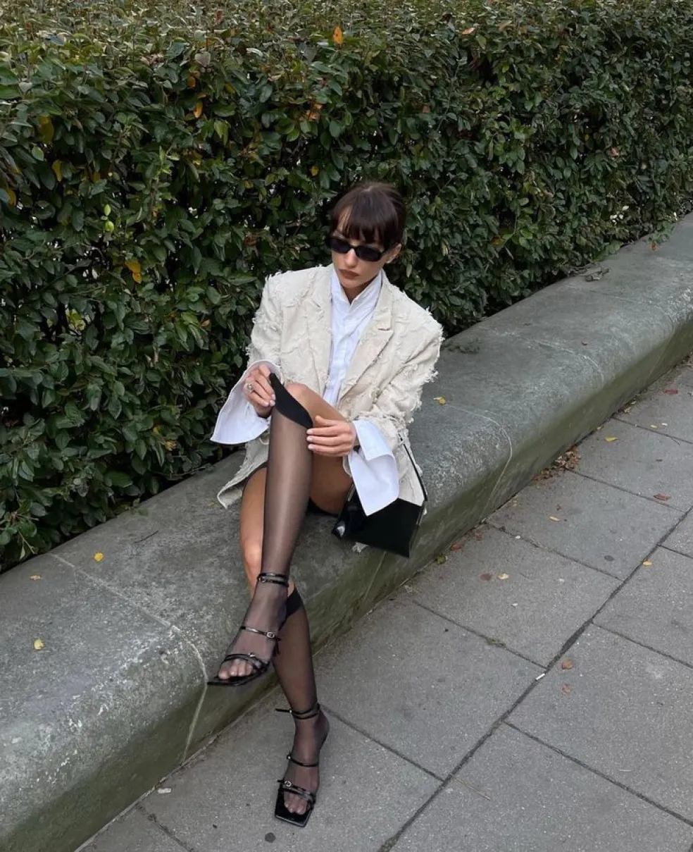 Čierne silonky v otvorených remienkových sandáloch ako súčasť elegantného mestského outfitu