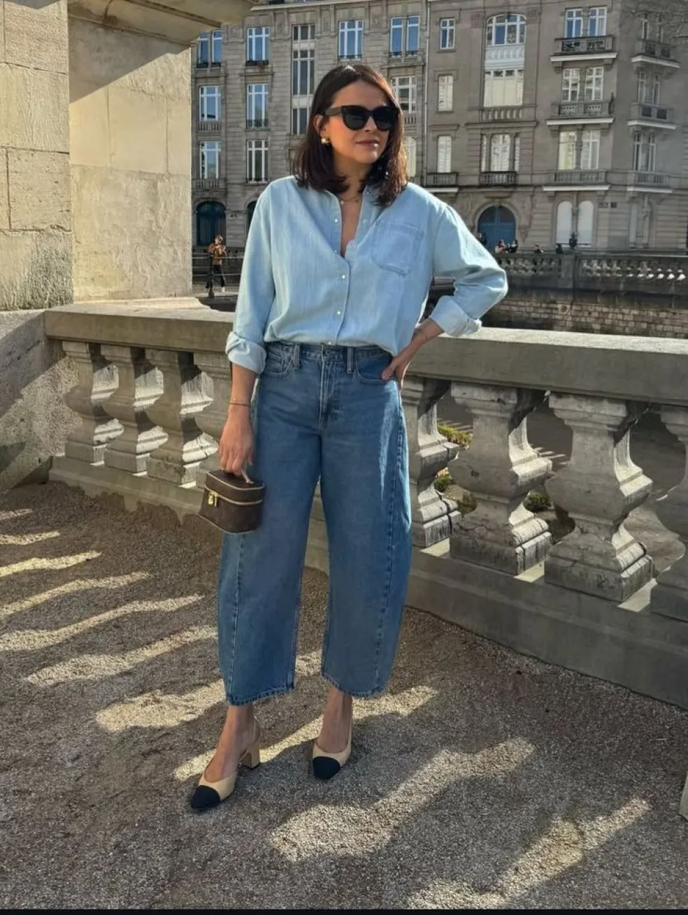 Denim on denim outfit so svetlomodrou džínsovou košeľou, širokými modrými džínsami, dvojfarebnými lodičkami a malou hnedou kabelkou