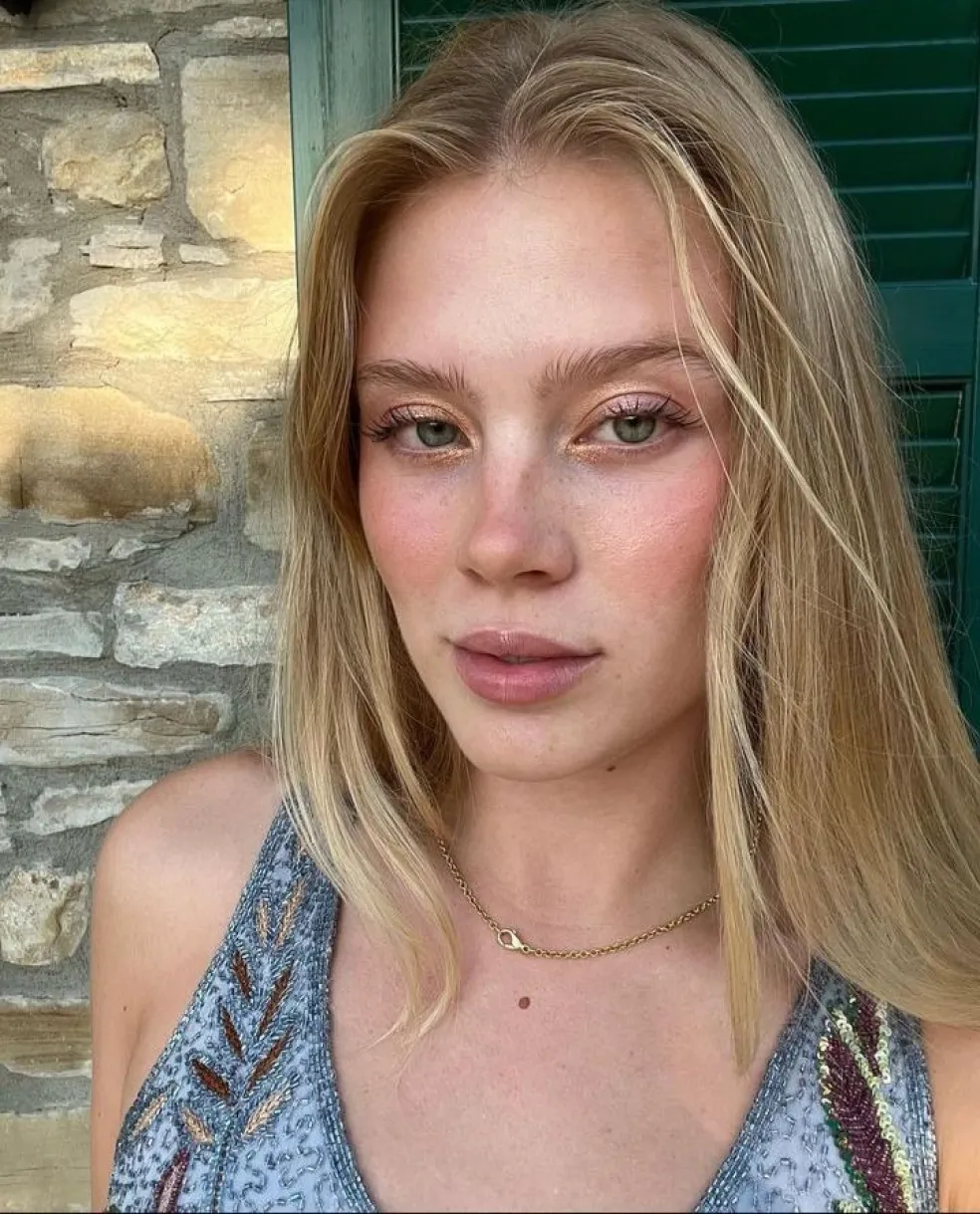 Blondínka so zlatistými vlasmi a priesvitným ružovým rúžom, ktorý jemne zvýrazňuje prirodzenú farbu pier a vytvára svieži vzhľad