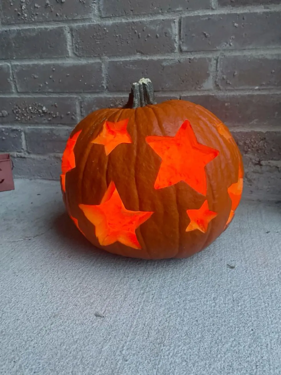 Vyrezávaná halloweenska tekvica so svietiacimi hviezdami ako originálna jesenná dekorácia na Halloween.