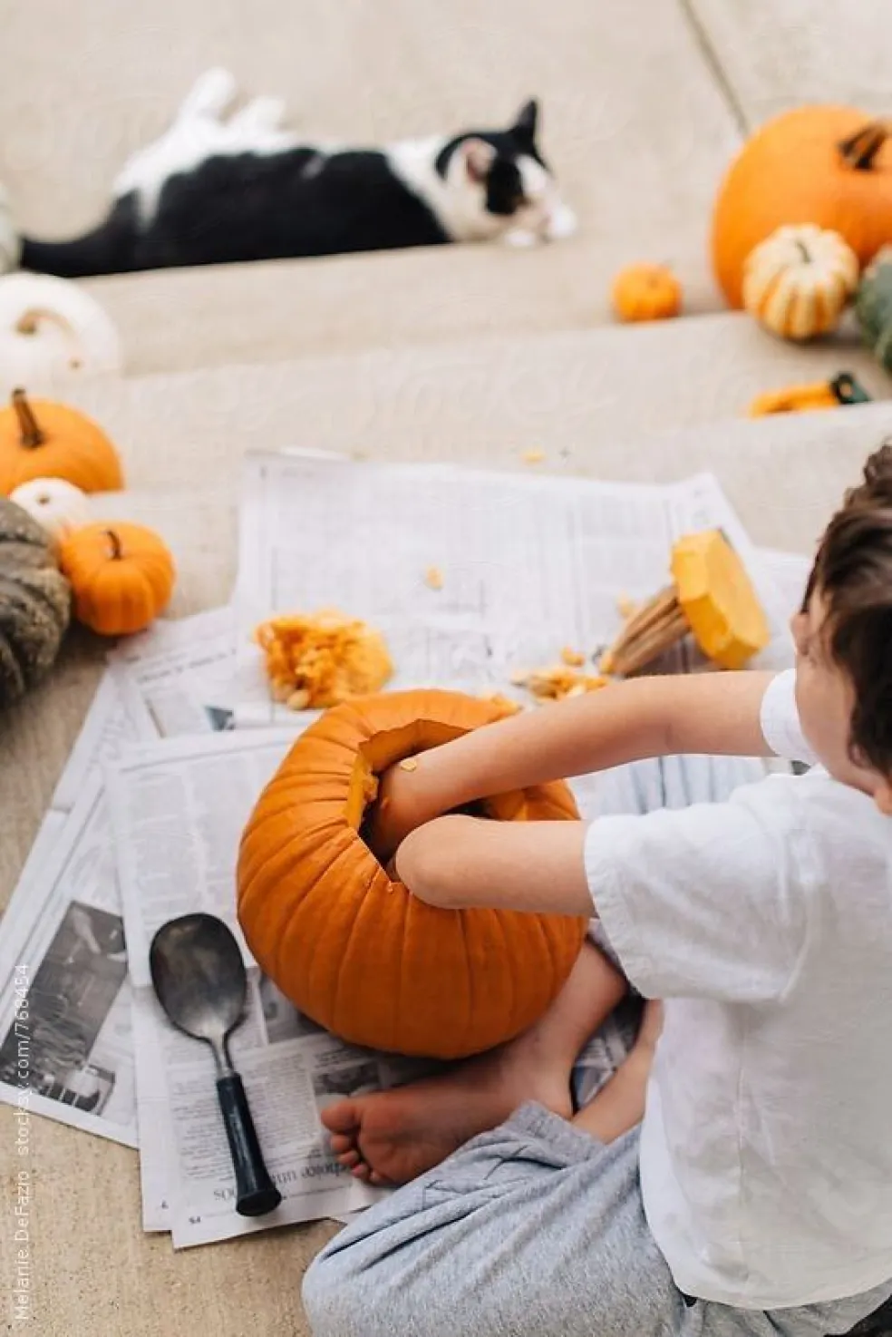 Dieťa vydlabáva halloweensku tekvicu a rukami vyberá dužinu a semienka počas prípravy na vyrezávanie tekvice