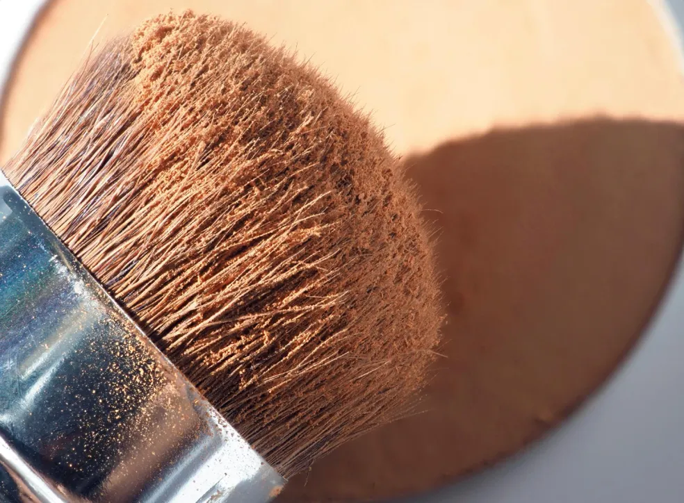 Detail kozmetického štetca so štetinami zanesenými púdrom – pravidelné čistenie a výmena opotrebovaných štetcov na make-up