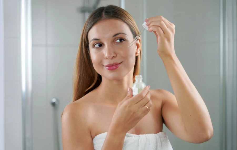 Žena nanáša kvapku retinolového séra na tvár pred spaním